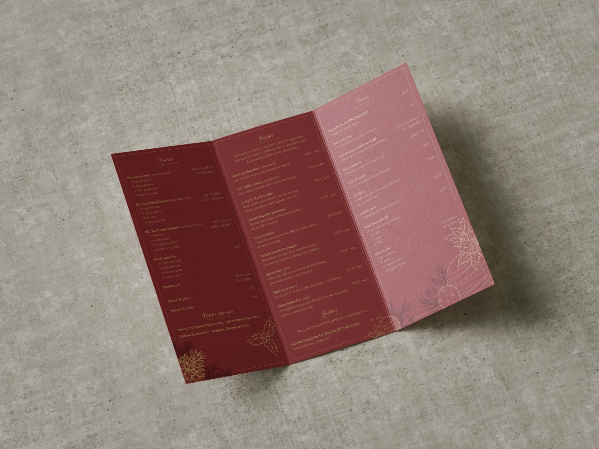 Menu de Noël déplié sur une table en béton, avec des décorations florales dorées.