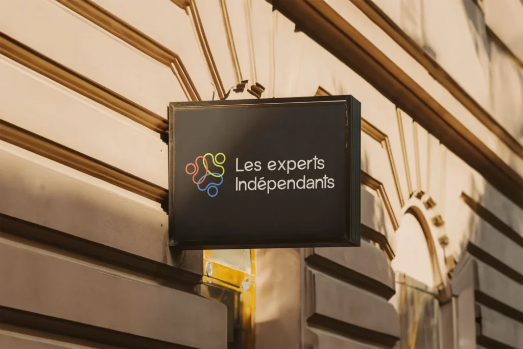 Panneau d'affichage extérieur avec le logo coloré de "Les experts Indépendants" et le texte associé.