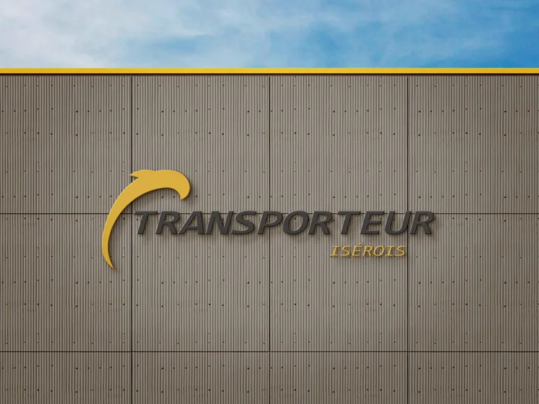 Logo de TRANSPORTEUR ISEROIS sur un mur de bâtiment gris sous un ciel bleu.