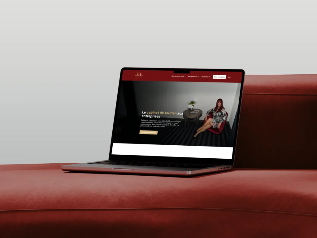 Capture d'écran d'un site web sur un ordinateur portable affichant une femme assise dans un fauteuil rouge, texte en français sur le soutien aux entreprises.