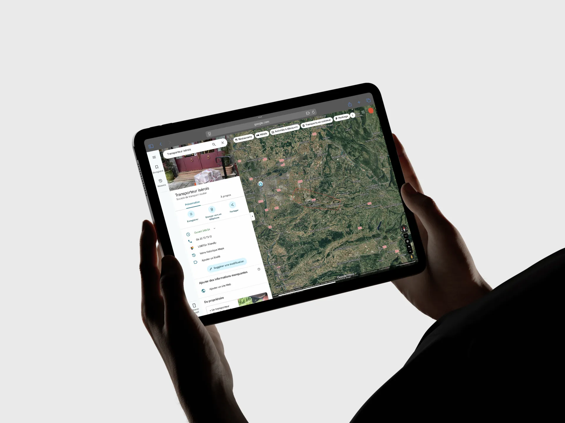 Personne tenant une tablette affichant une carte satellite et une liste d'informations