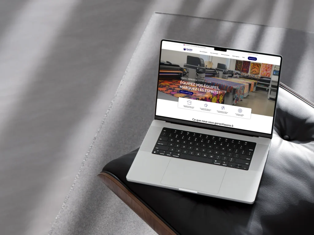 Ordinateur portable ouvert affichant un site web avec des imprimantes et des textiles colorés. Le slogan « ÉQUIPEZ VOS ÉQUIPES, MARQUEZ LES ESPRITS ! » est visible.