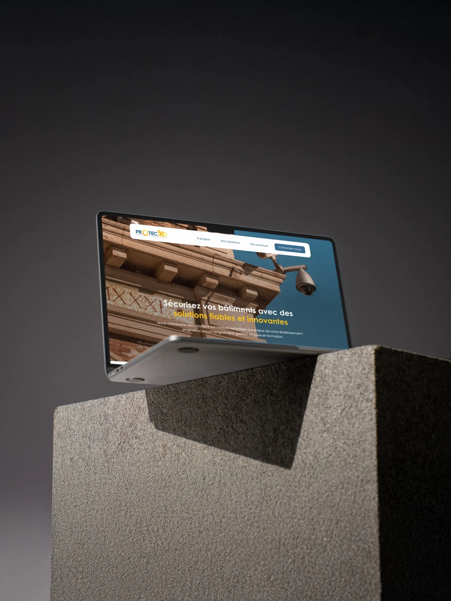 Ordinateur portable affichant un site web de sécurité pour bâtiments avec un slogan et une image de caméra de surveillance.