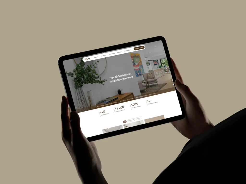Tablette affichant un site web de rénovation intérieure avec des statistiques : +20 projets, +1 000 clients, 100% satisfaction, 10 ans d'expérience.
