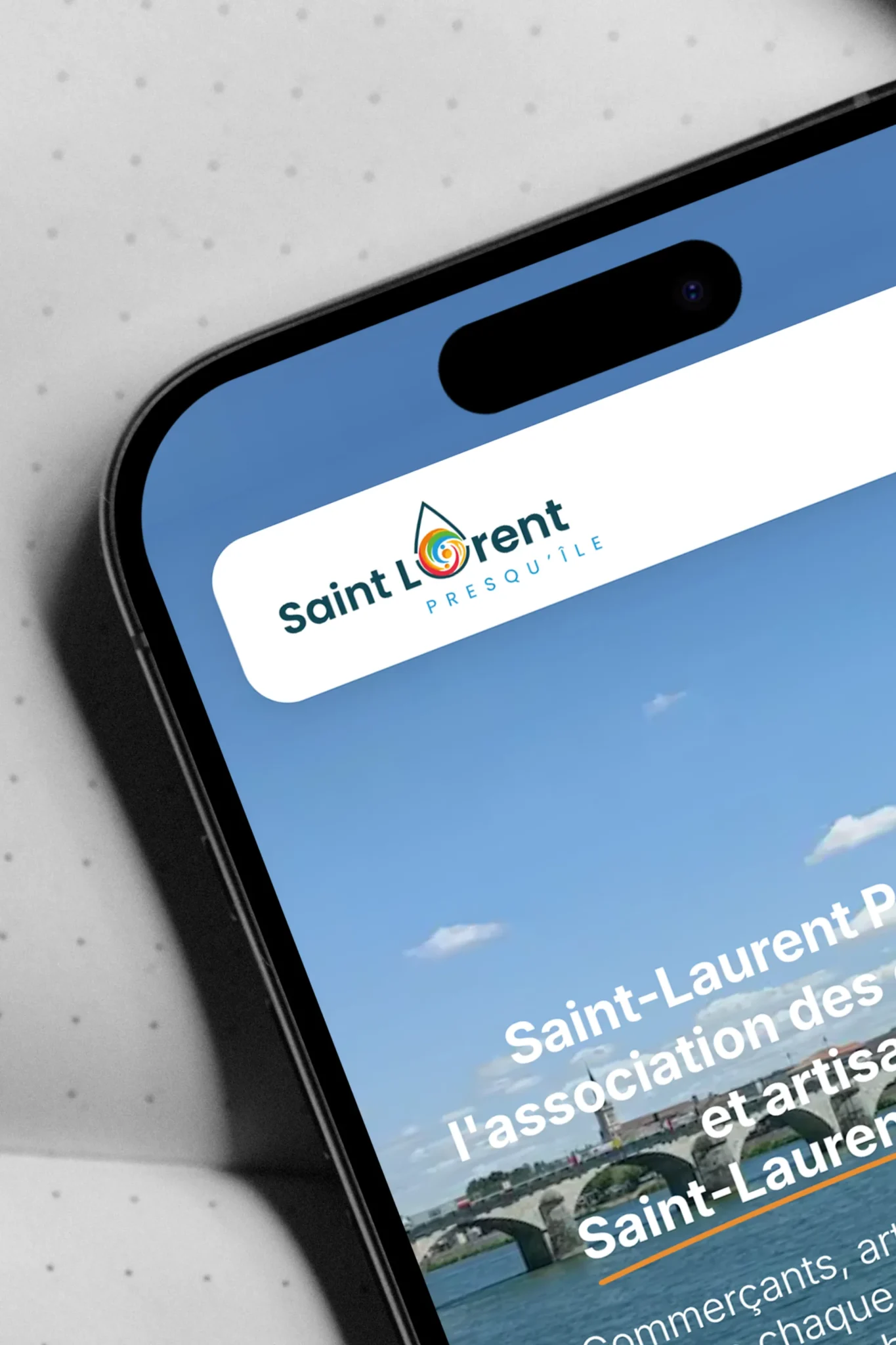 Logo de Saint-Laurent avec un arc-en-ciel dans une goutte d'eau, sur un écran de téléphone.
